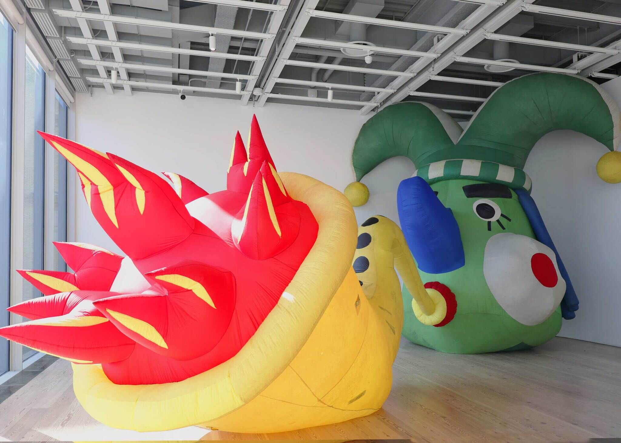 Two large colorful inflatable sculptures, one red and yellow spiky piece and a green jester-like figure.