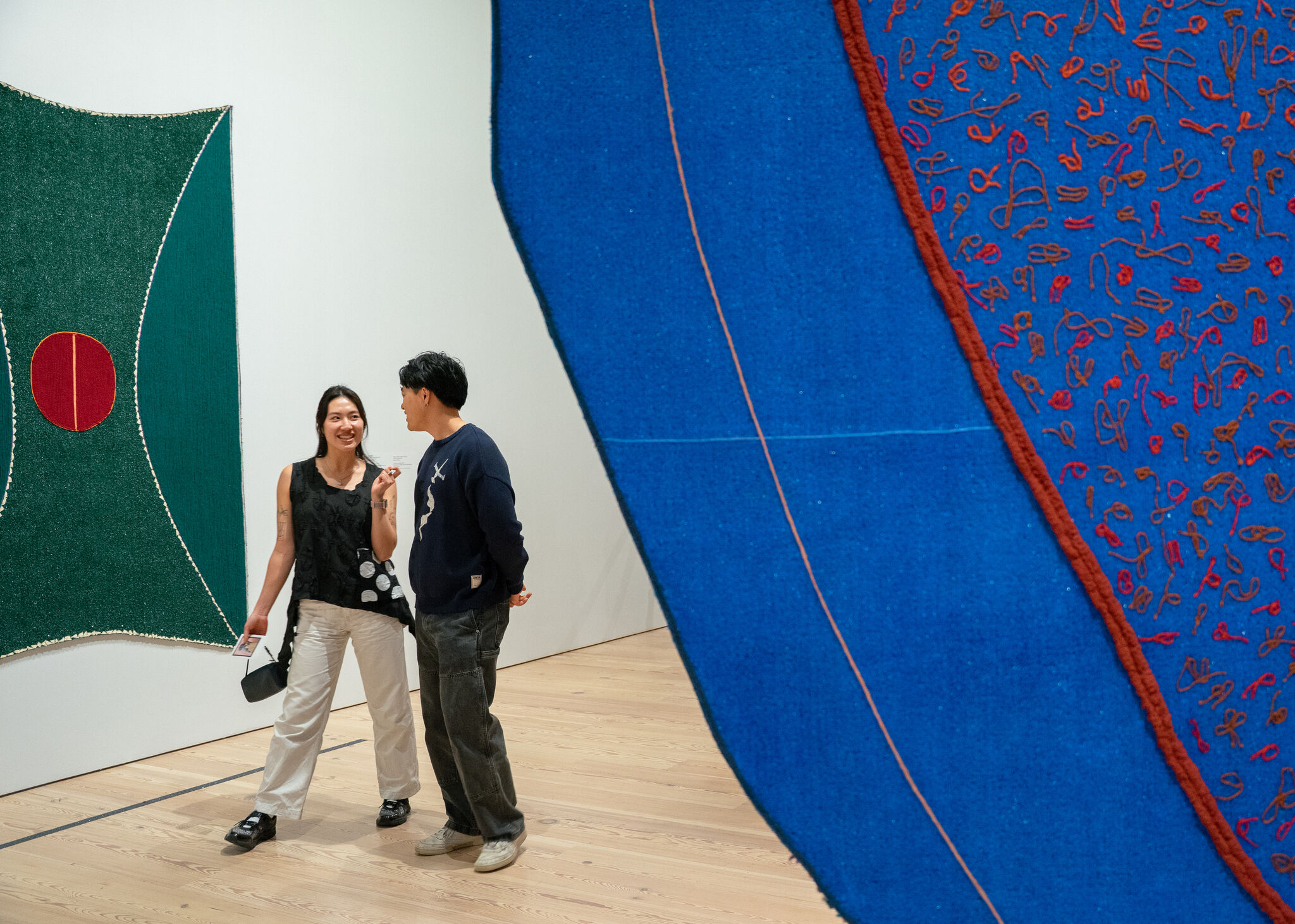 Two people walking together between artwork in a gallery.