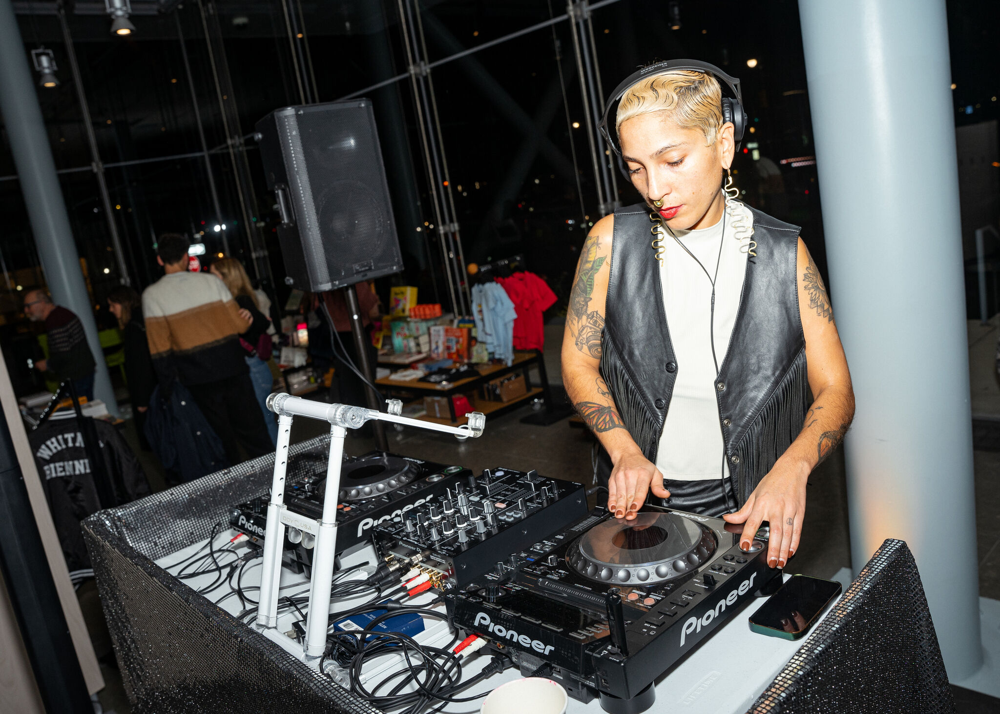 A DJ with headphones adjusts a Pioneer mixer and turntable during a nighttime event.