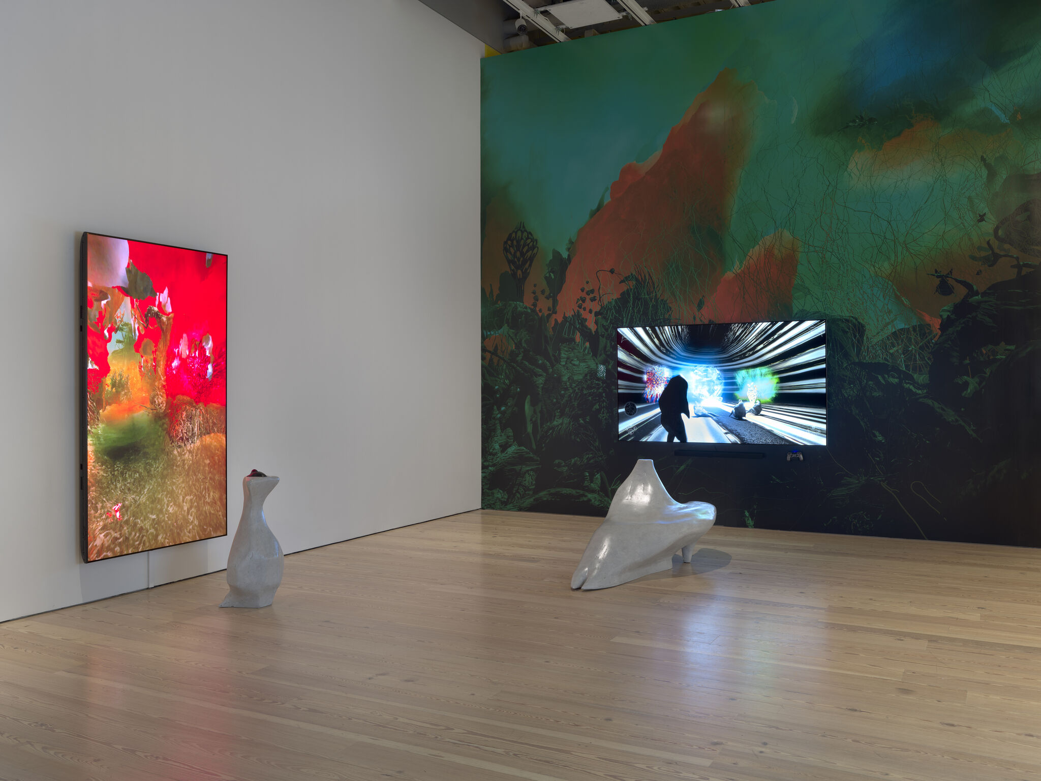 Two large digital screens display colorful abstract scenes on gallery walls with smooth sculptural benches.