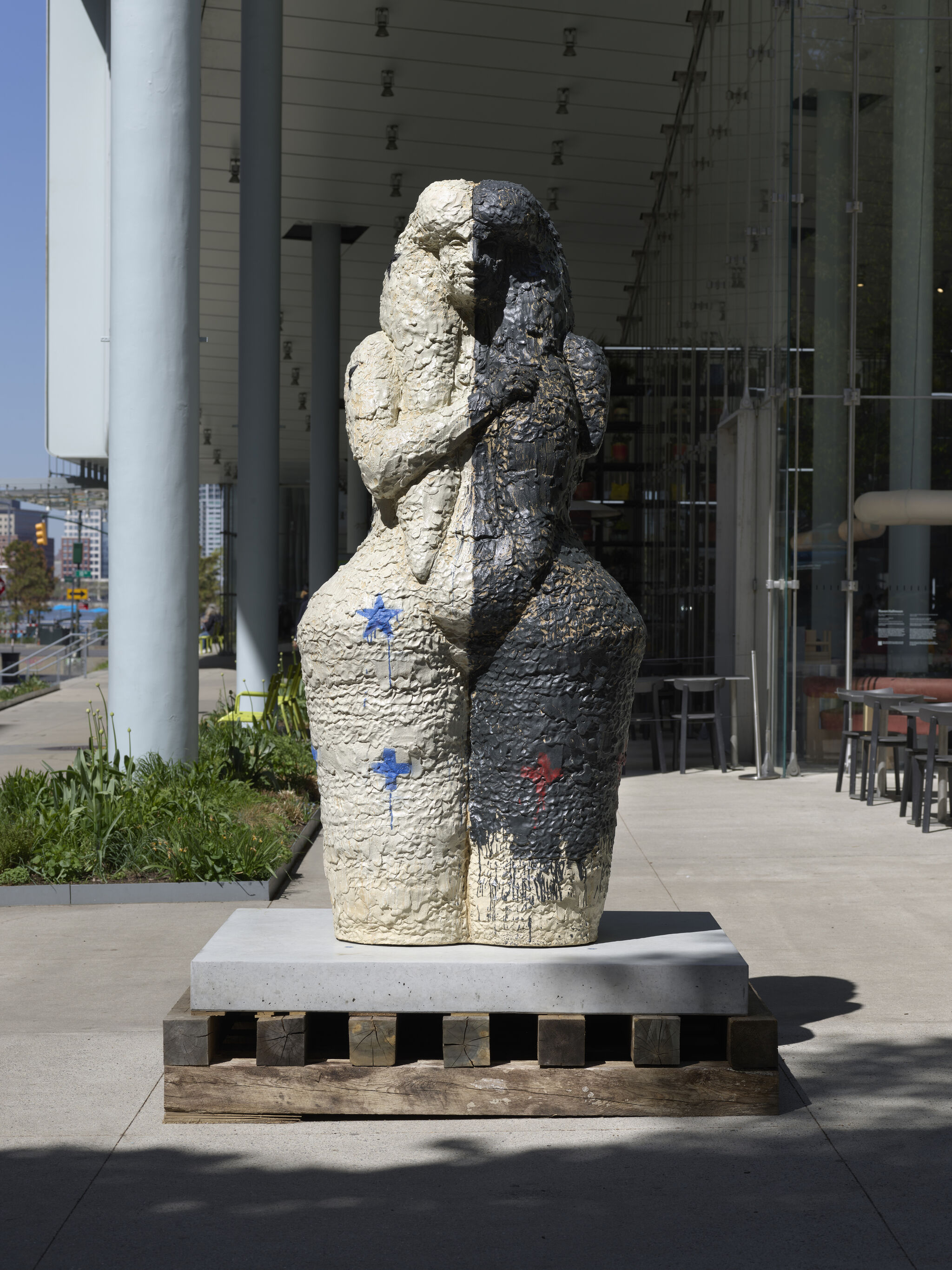 A textured sculpture of two fused female figures, one white and one black, embracing.