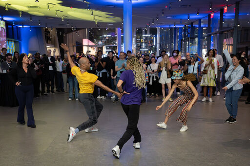Dancers performing an energetic routine in the center while a crowd watches and cheers.