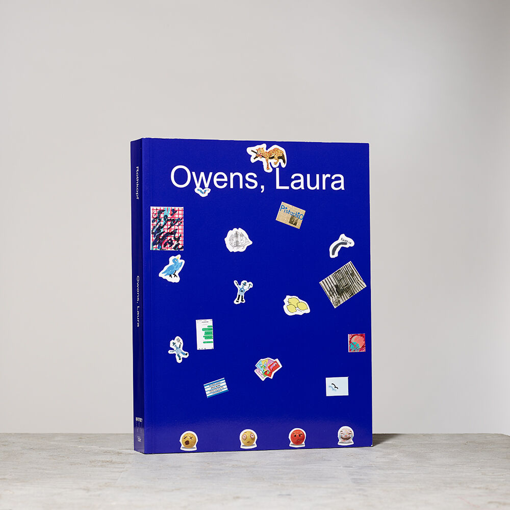 A blue art book titled Owens, Laura decorated with small colorful stickers on the cover.