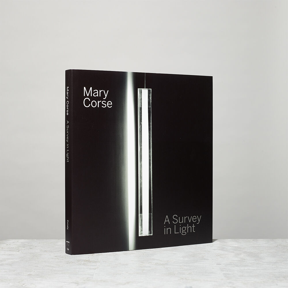 A black book titled Mary Corse: A Survey in Light stands upright on a light surface.