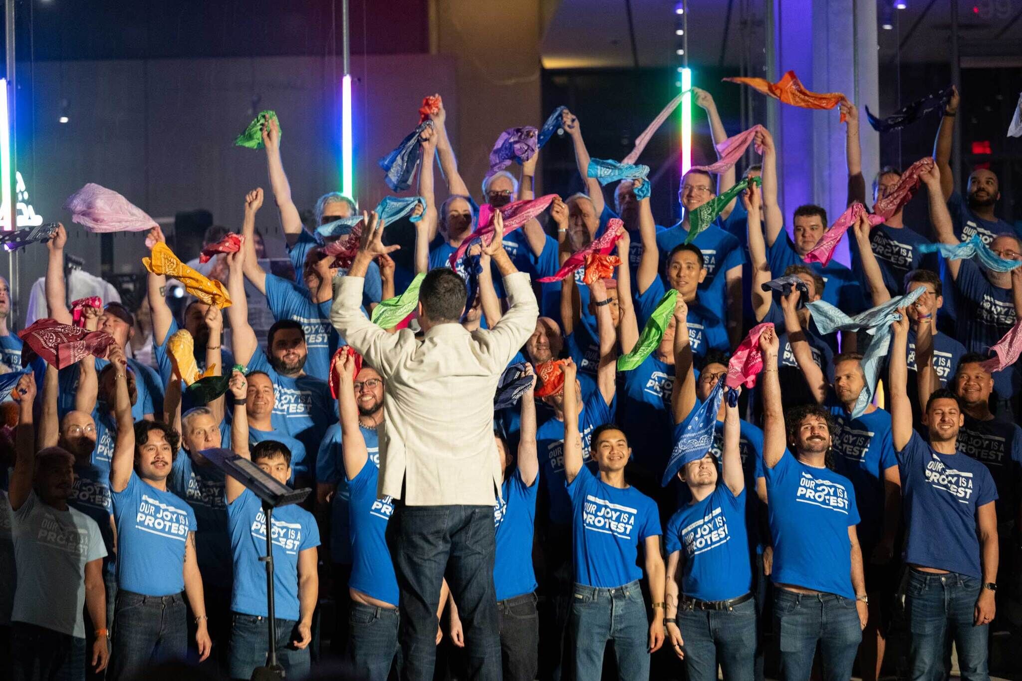Chorus singers hold up coloful bandanas during a performance in front of the Whitney Musuem