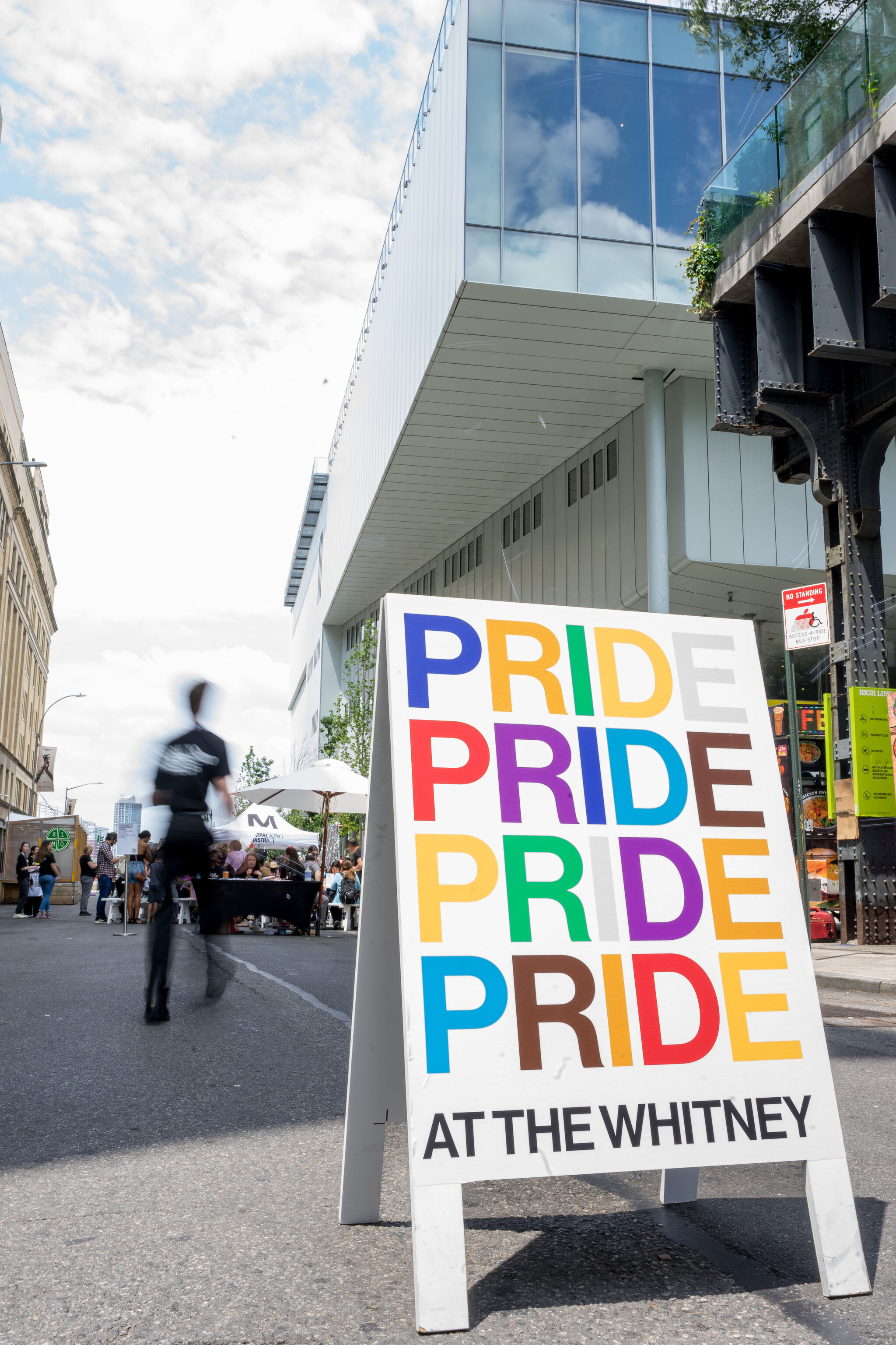 A sandwich-board sign reading PRIDE in colorful letters stands outside the Whitney museum.