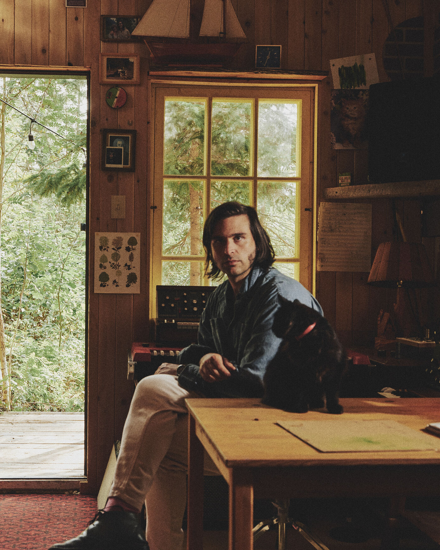 Musician Mathieu David Gagnon sitting at a table with his cat, surrounded by warm wood interiors. 
