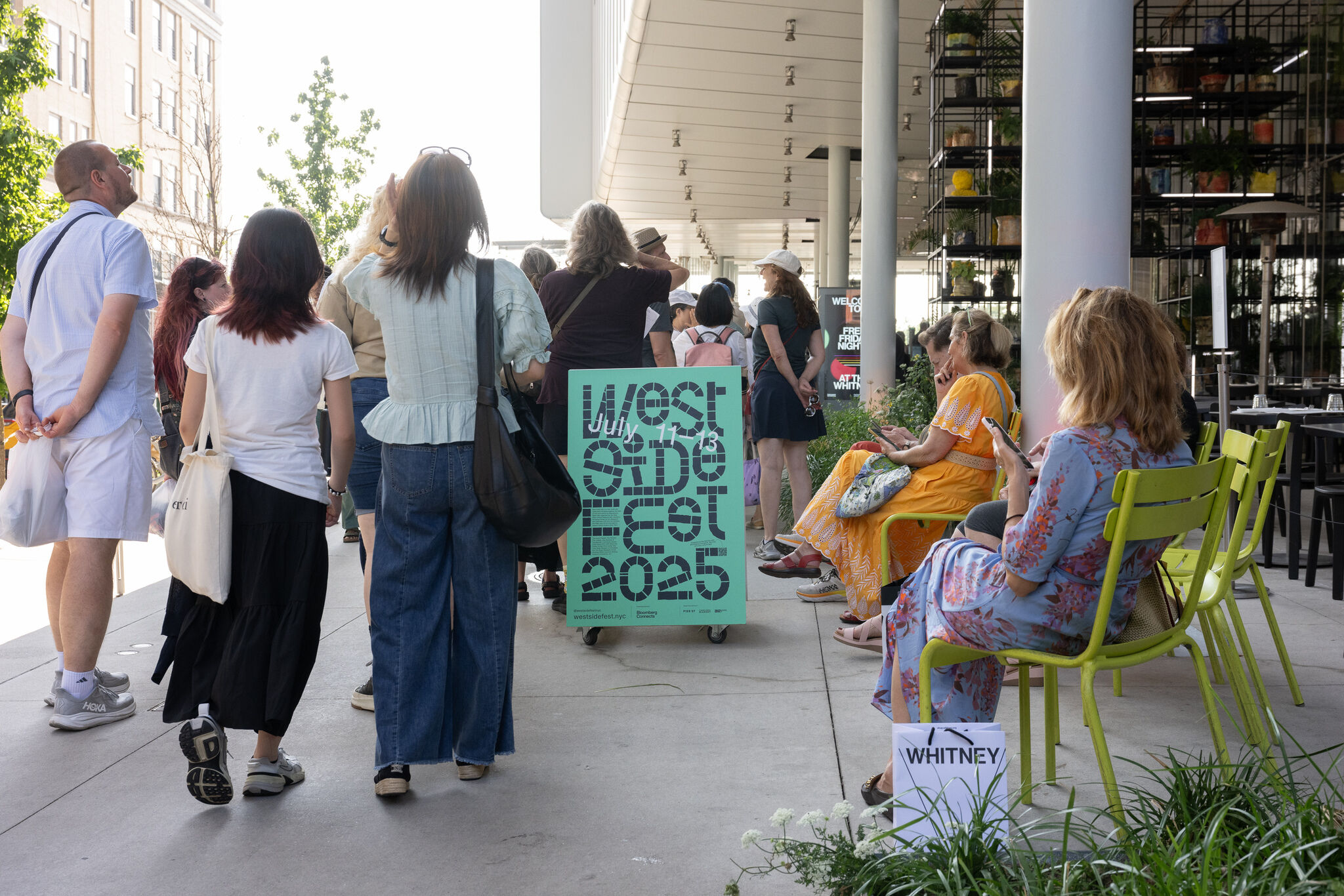 A crowd gathers under a canopy near a teal West Side Fest 2025 sign.