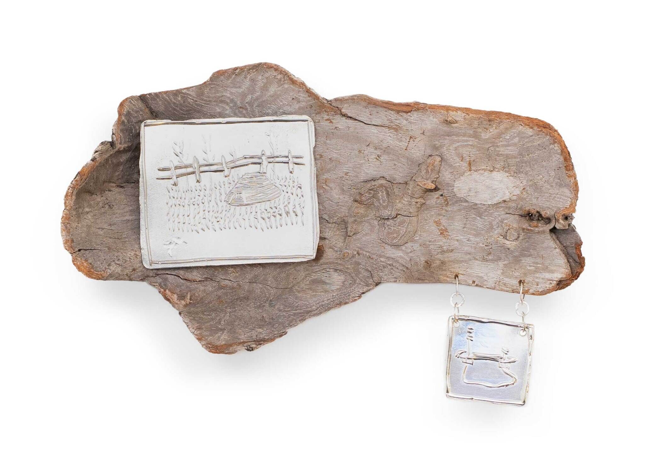 Weathered wood panel with linked silver rectangular charms engraved with a fence and rock design.