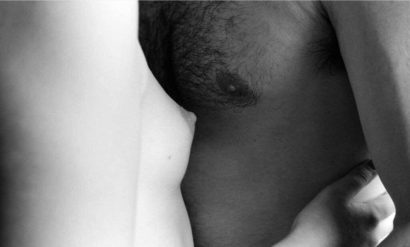Two bare torsos pressed together with a hand resting on the lower back.