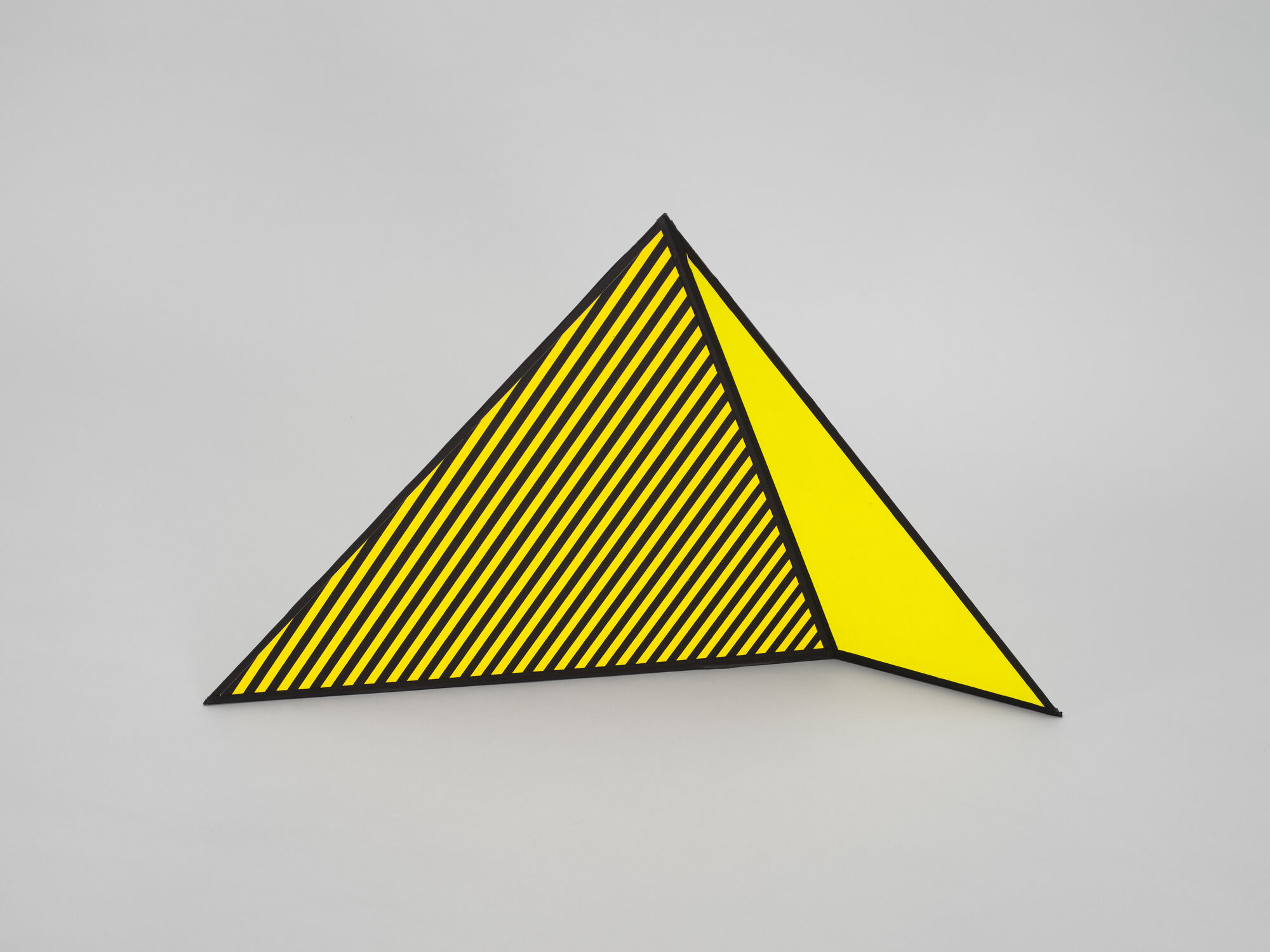 A yellow triangular warning sign with black diagonal stripes standing against a light gray background.