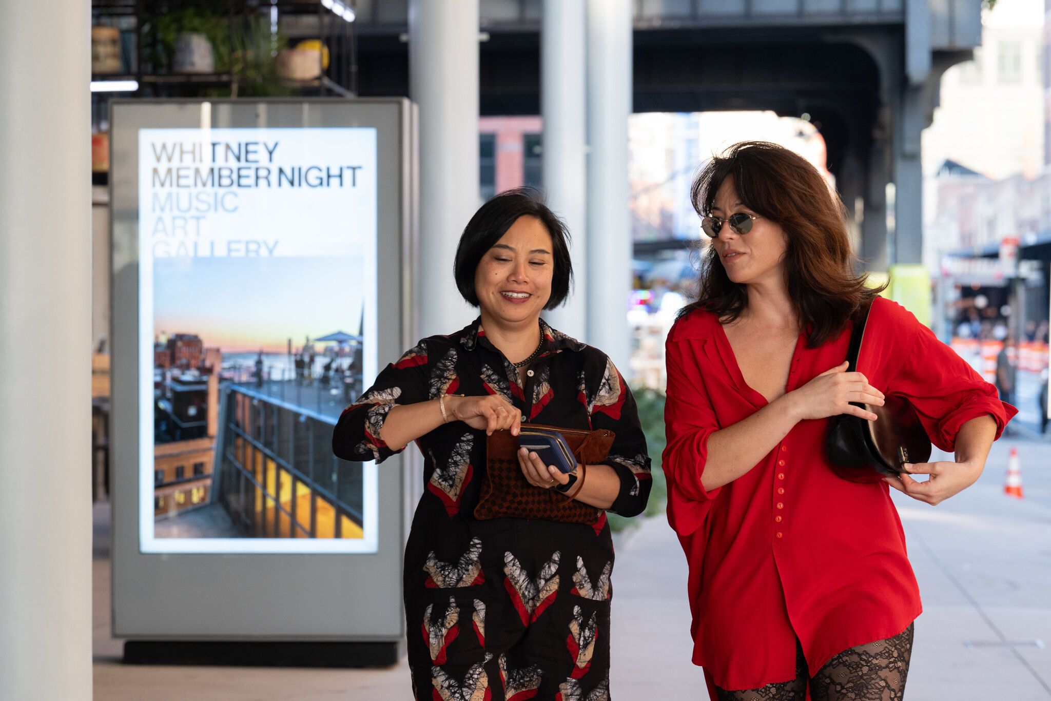 Two women walking side by side against a city backdrop