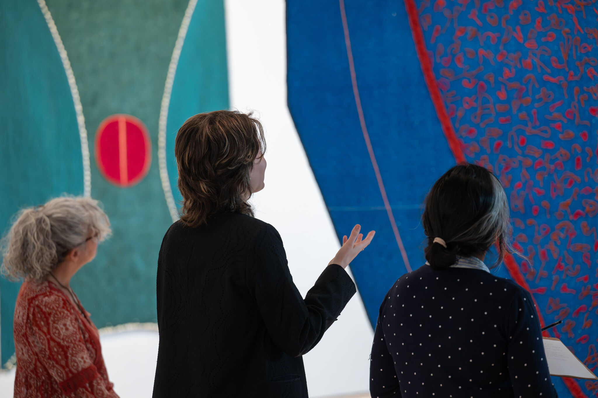 Three people viewing Teresa Baker's artwork in the Whitney Biennial exhibition. 