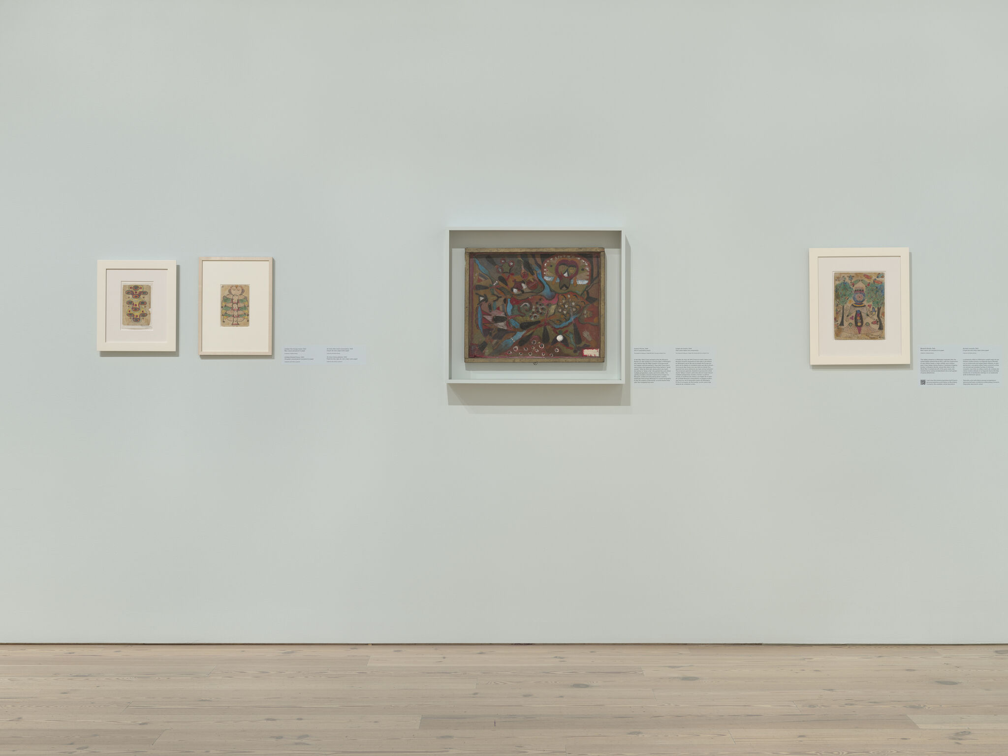 Five framed artworks evenly spaced on a pale gallery wall above a wooden floor.