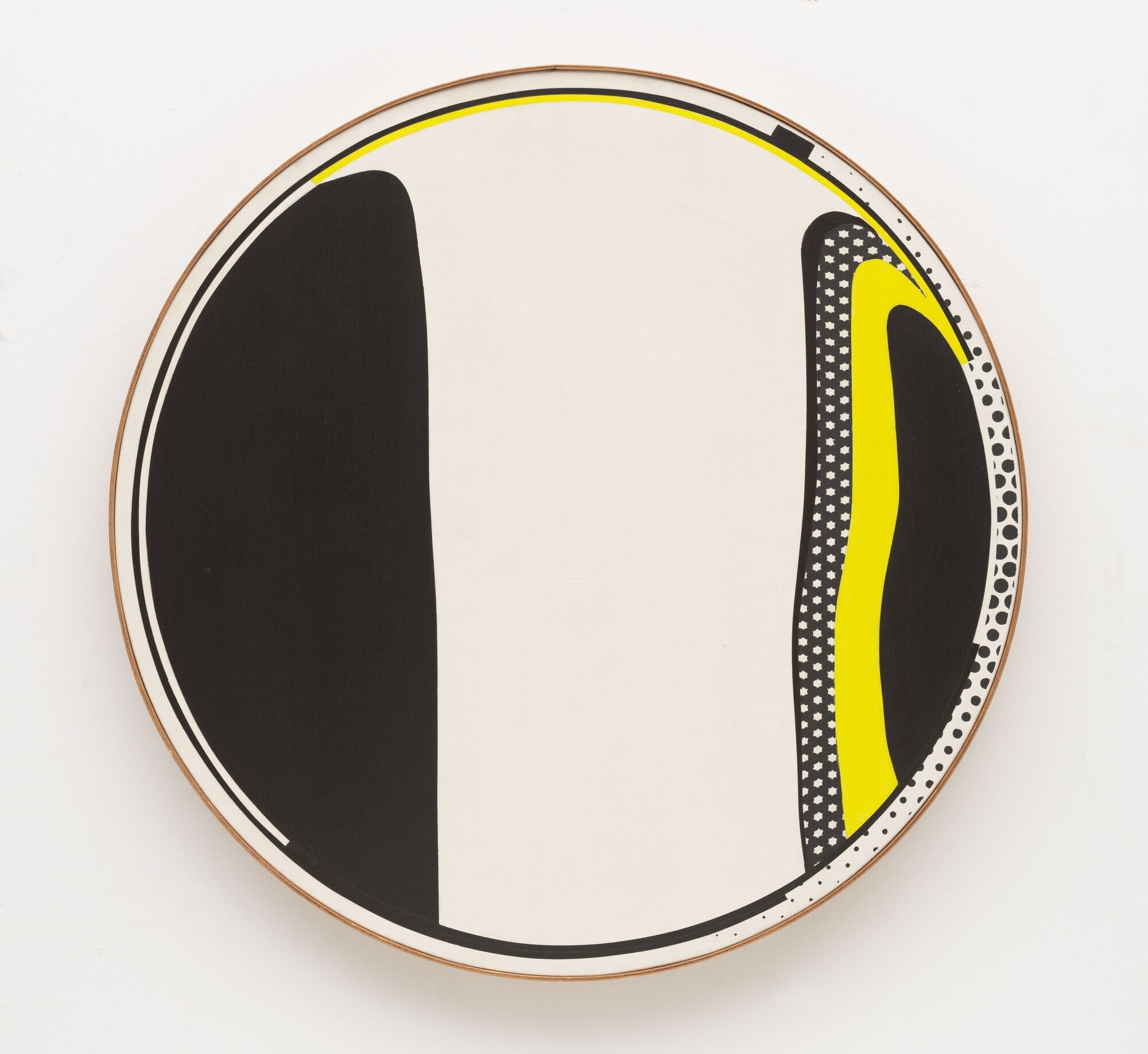 Circular abstract artwork with bold black shapes, yellow accents, and dotted border hanging on a wall.