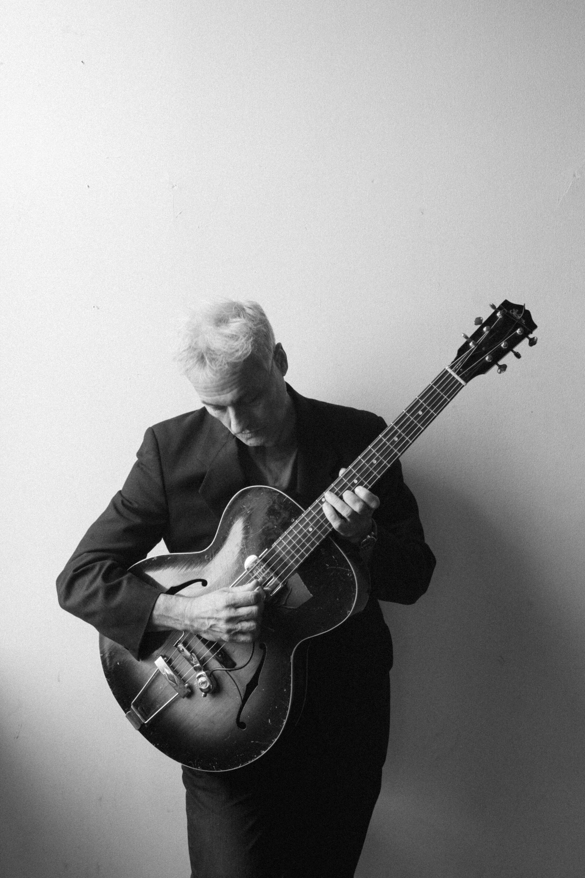 B&W photo of Marc Ribot holding his guitar.