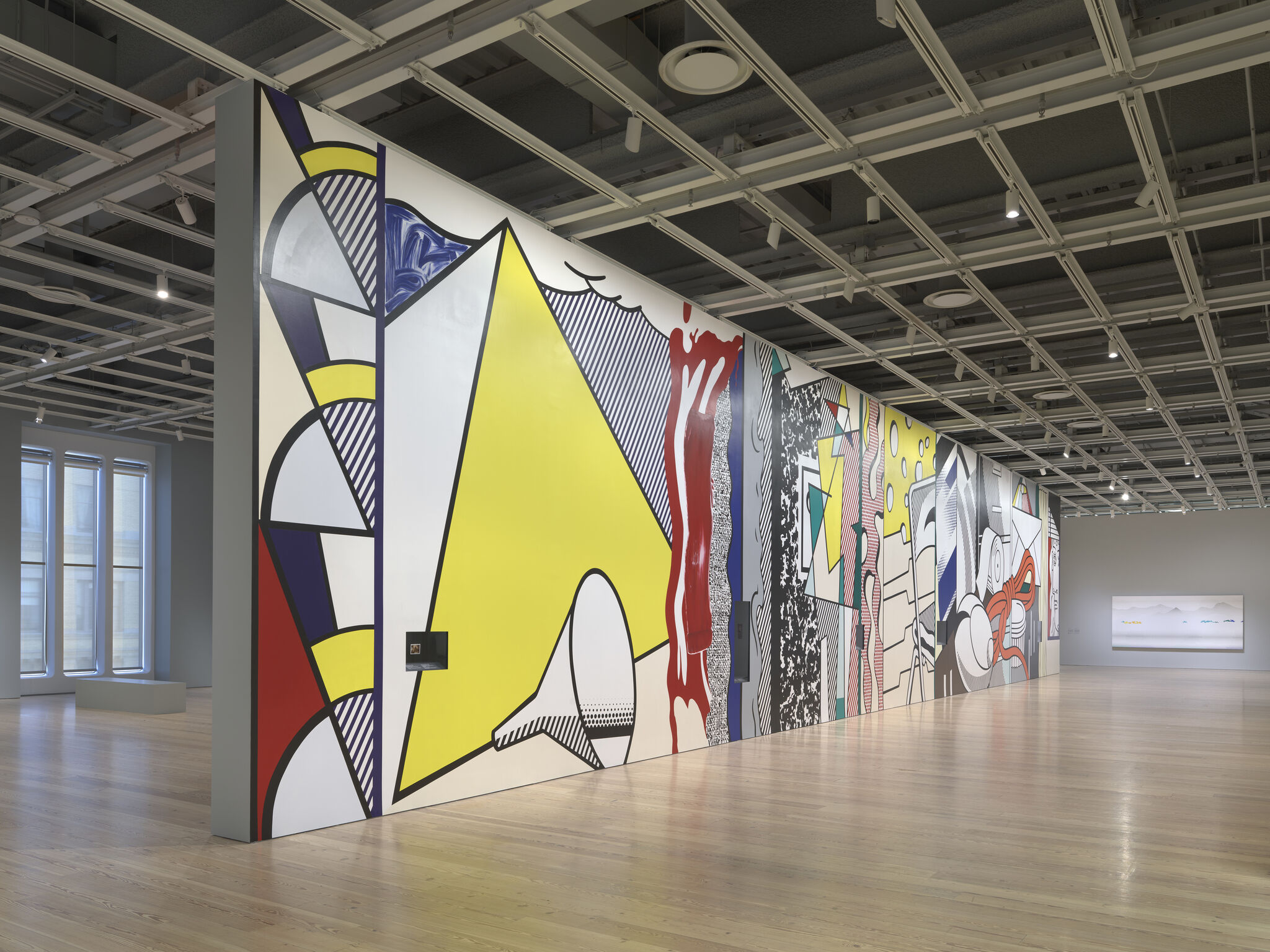 Large colorful geometric pop-art mural spans a gallery wall under exposed ceiling grid.