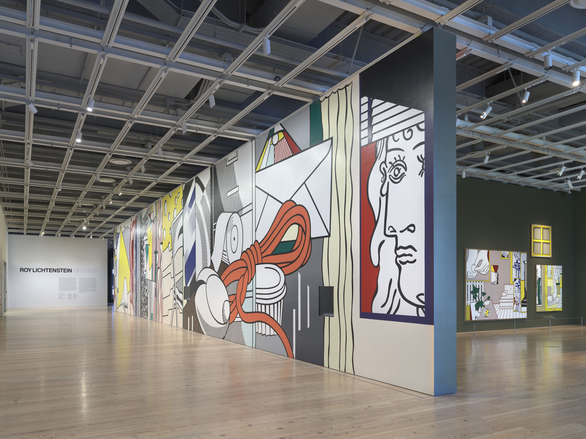 A large Roy Lichtenstein mural covers the gallery wall with bold comic-style images.