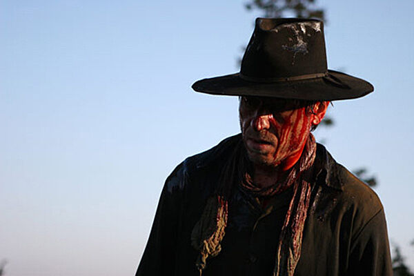 A man in a cowboy hat from a film still.