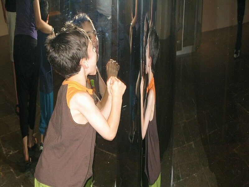 A child plays while looking in the mirror
