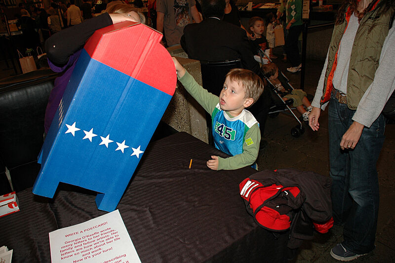 A boy plays with a cardboard mailbox
