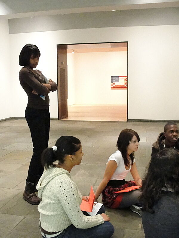 A youth education group sits on the floor of a gallery.