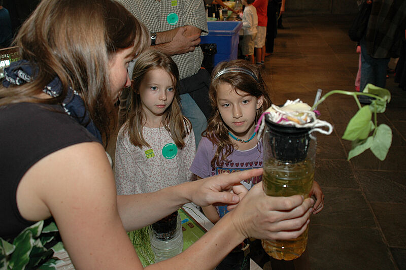 An artist shows children a plant project